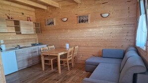 Un interno in legno con un tavolo da pranzo, sedie, un divano e un angolo cottura.