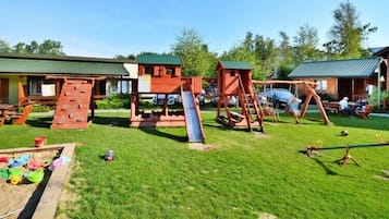 En legeplads med rutchebane, gynger og klatrestrukturer.