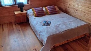A wooden room with a bed, a nightstand, and a window. - Comfortable holiday home very close to the beach (Sianozety)