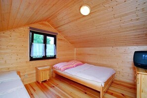 A single bed with a pink blanket, a small wooden nightstand, a television, and a window with curtains. - Holiday home with a terrace, close to the sea (Sianozety)