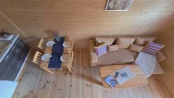 Et træpanelt interiør med et spisebord og stole, en sofa og et lille sofabord.