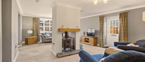 A living room with a fireplace, sofas, a television, and a window with curtains.