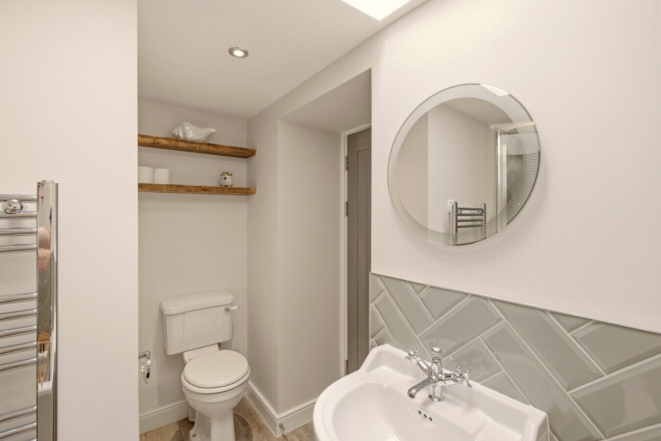 Een badkamer met toilet, wastafel, spiegel en handdoekhouder.