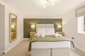 A bedroom with a bed, nightstands, a mirror, and a window.