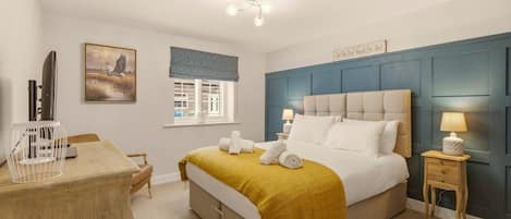 A bedroom with a bed, bedside tables, a desk, a chair, a window with blinds, and a painting on the wall.