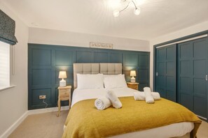 Une chambre à coucher comprenant un lit, des lampes de chevet, une tête de lit, un panneau décoratif fixé au mur et une armoire.