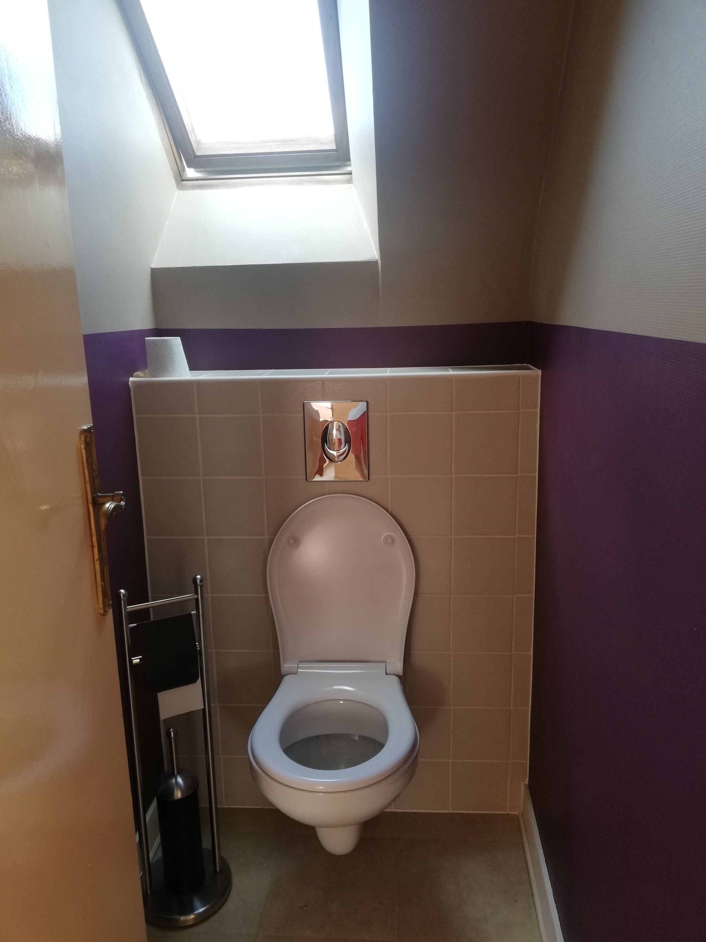 Une salle de bain équipée de toilettes, d’un sèche-mains et d’une fenêtre.