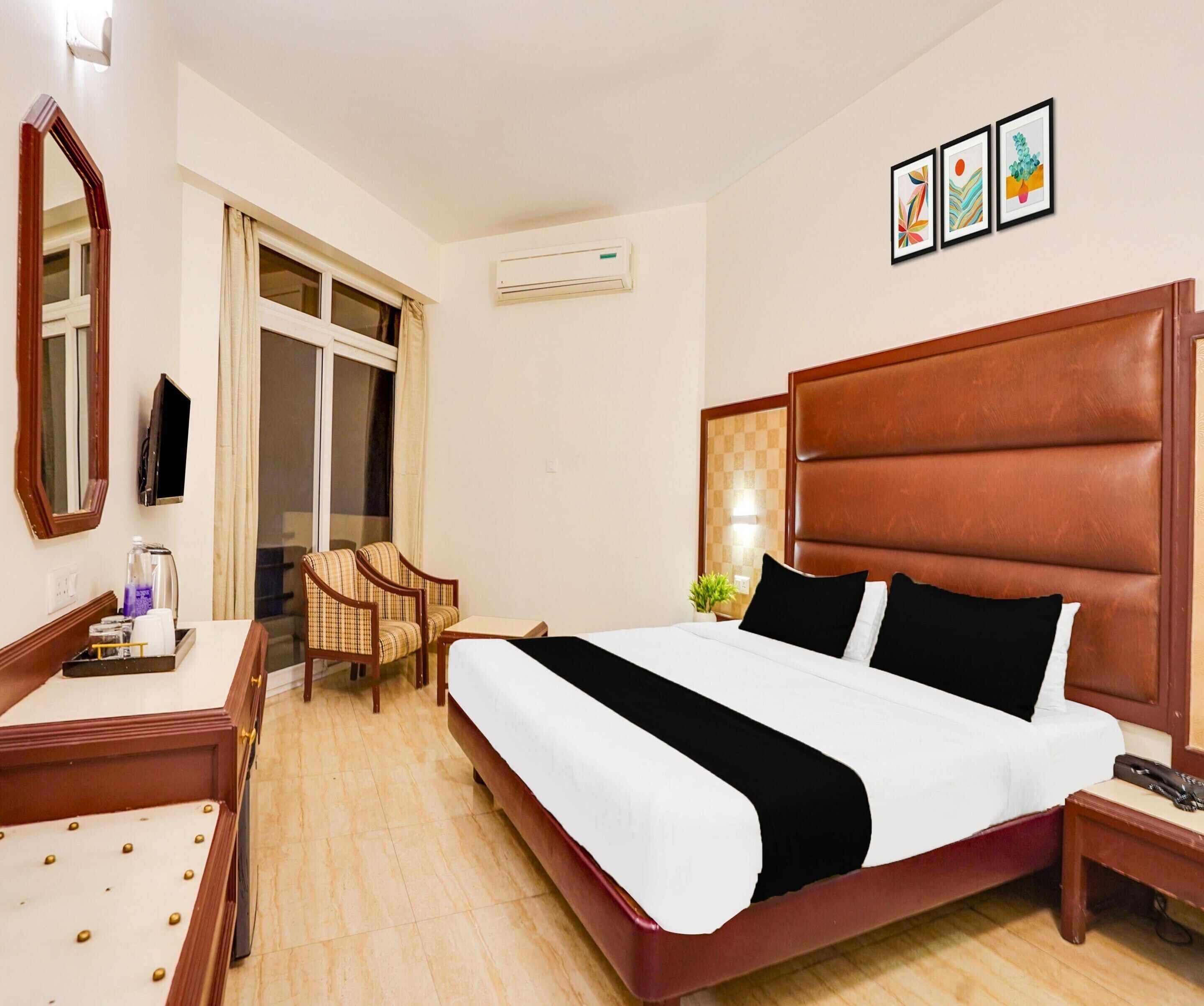 A hotel room with a bed, a desk, a chair, a TV, and a window.