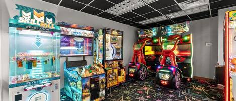 Een kamer met speelautomaten, waaronder 'Skill Fall' en 'Revolution', en een tapijt met stervenspatroon.