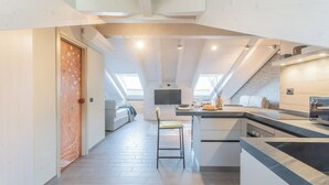 Een moderne keuken met dakramen, een eethoek en een gang naar een slaapkamer.