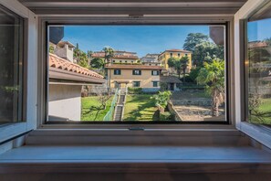 Une vue à travers une fenêtre donnant sur un quartier résidentiel, avec des maisons, une pelouse et un escalier.