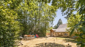 A stone building with a sloped roof, surrounded by trees and a grassy yard. - Peaceful country cottage - 6 guests (Nort-sur-Erdre)