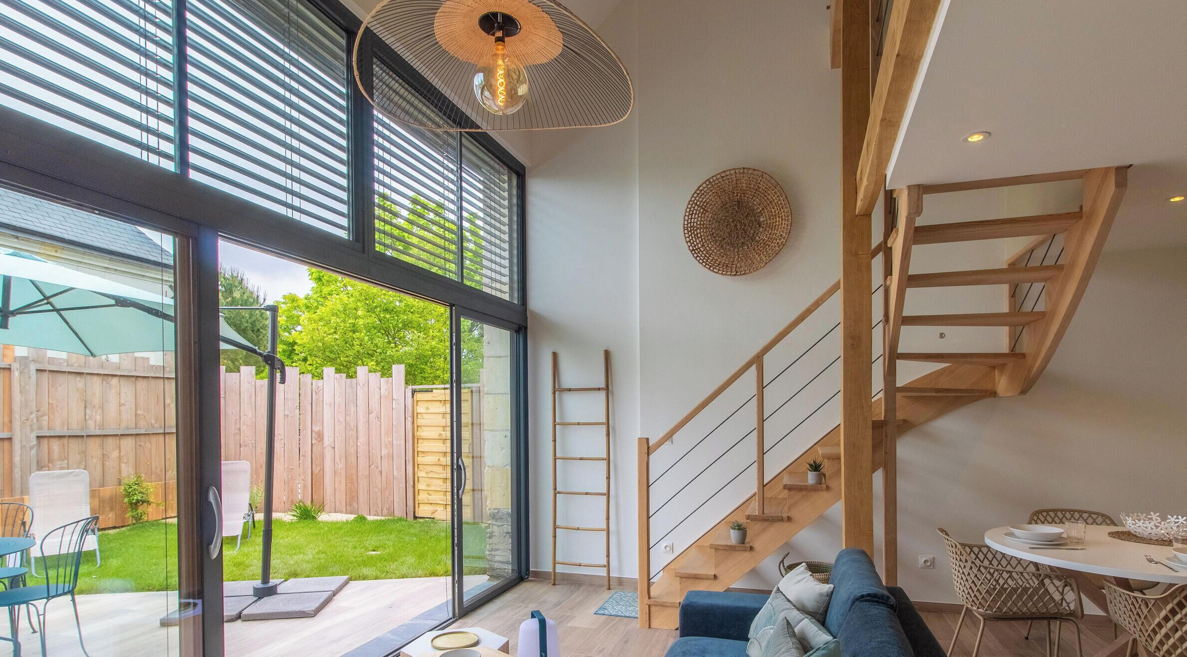 Un intérieur moderne avec un escalier, un coin repas et une vue sur l’extérieur.