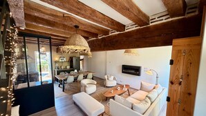 Ein modernes Wohnzimmer mit Holzboden, einem Essbereich und einer durchgehenden Tür erreichbaren Küche.