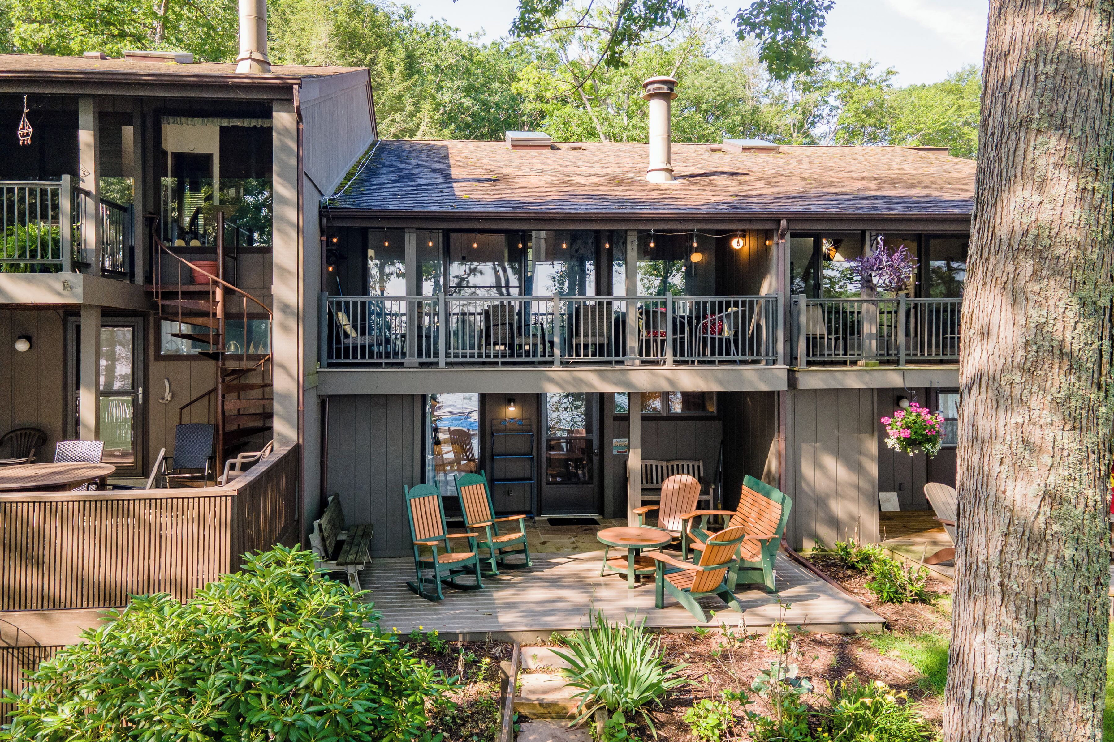 Un bâtiment à deux étages doté d’un balcon, d’un espace extérieur aménagé avec des chaises et d’une terrasse en bois.