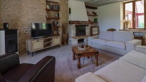 Ein Wohnzimmer mit Steinwand, Kamin, Fernseher, Sofa und Couchtisch.