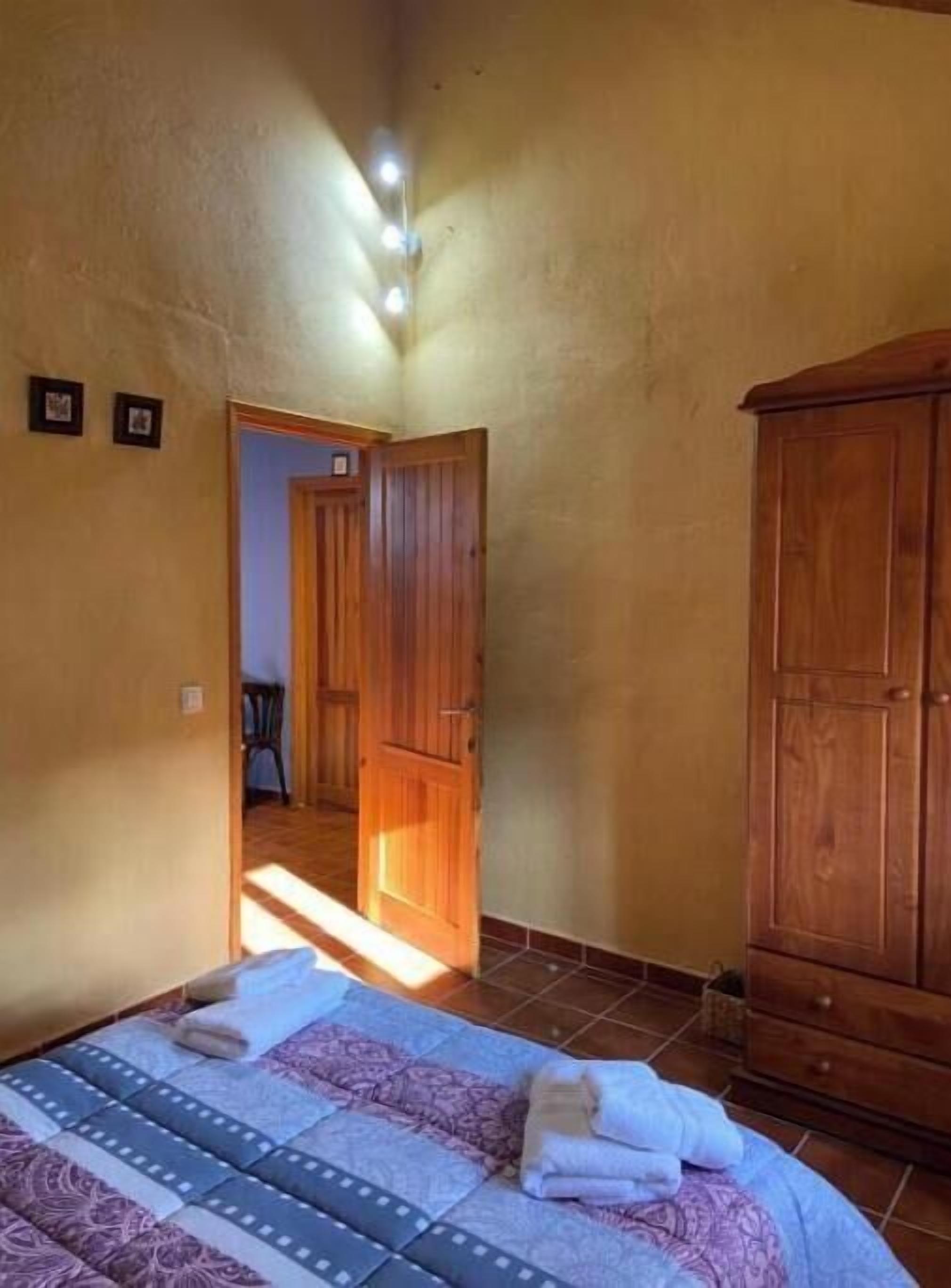 Un dormitorio con cama, armario de madera y puerta que da a otra habitación.