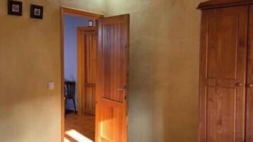 Un dormitorio con cama, armario de madera y puerta que da a otra habitación.