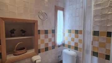 A bathroom with a toilet, sink, and shower area.