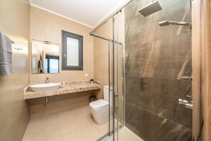 Ein modernes Badezimmer mit einer gläsernen Dusche, einem Waschbecken mit Marmorplatte und einer Toilette.