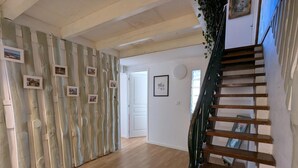 Eine Treppe mit Holzbalken und Metallgeländer, die zu einem Raum mit einer weißen Tür und einem gerahmten Bild an der Wand führt.