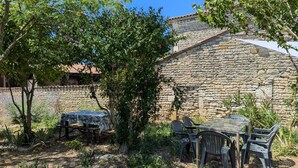 Ein Gebäude aus Stein mit einem Ziegeldach, umgeben von Grünflächen und einem Picknicktisch mit Stühlen.