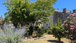 Ein Steingebäude mit Garten, einschließlich Lavendel und blühenden Büschen.