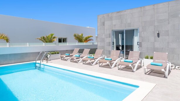 Uma piscina com espreguiçadeiras e um edifício moderno com fachada de concreto.