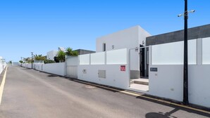 Um edifício moderno com entrada gradeada, céu claro e rua com linha amarela.