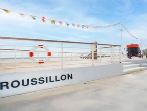 A waterfront promenade with a railing, a lifebuoy, and a sign that reads "ROUSSILLON". - Lovely air-conditioned apartment - 4 guests, mountain view (Canet-en-Roussillon)