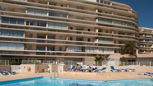Um hotel de vários andares com piscina e espreguiçadeiras.