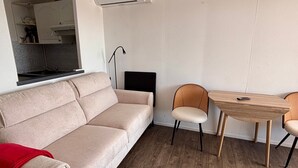 Uma sala de estar moderna com um sofá, duas poltronas, uma mesinha e um aparelho de ar condicionado.