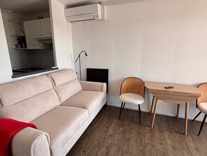 A modern living room with a sofa, two chairs, a small table, and an air conditioning unit. - Lovely air-conditioned apartment - 4 guests, mountain view (Canet-en-Roussillon)
