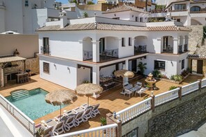 A two-story building with a swimming pool, outdoor seating, and a stone wall. - Villa Lara Pinta by Villa Plus (Nerja)