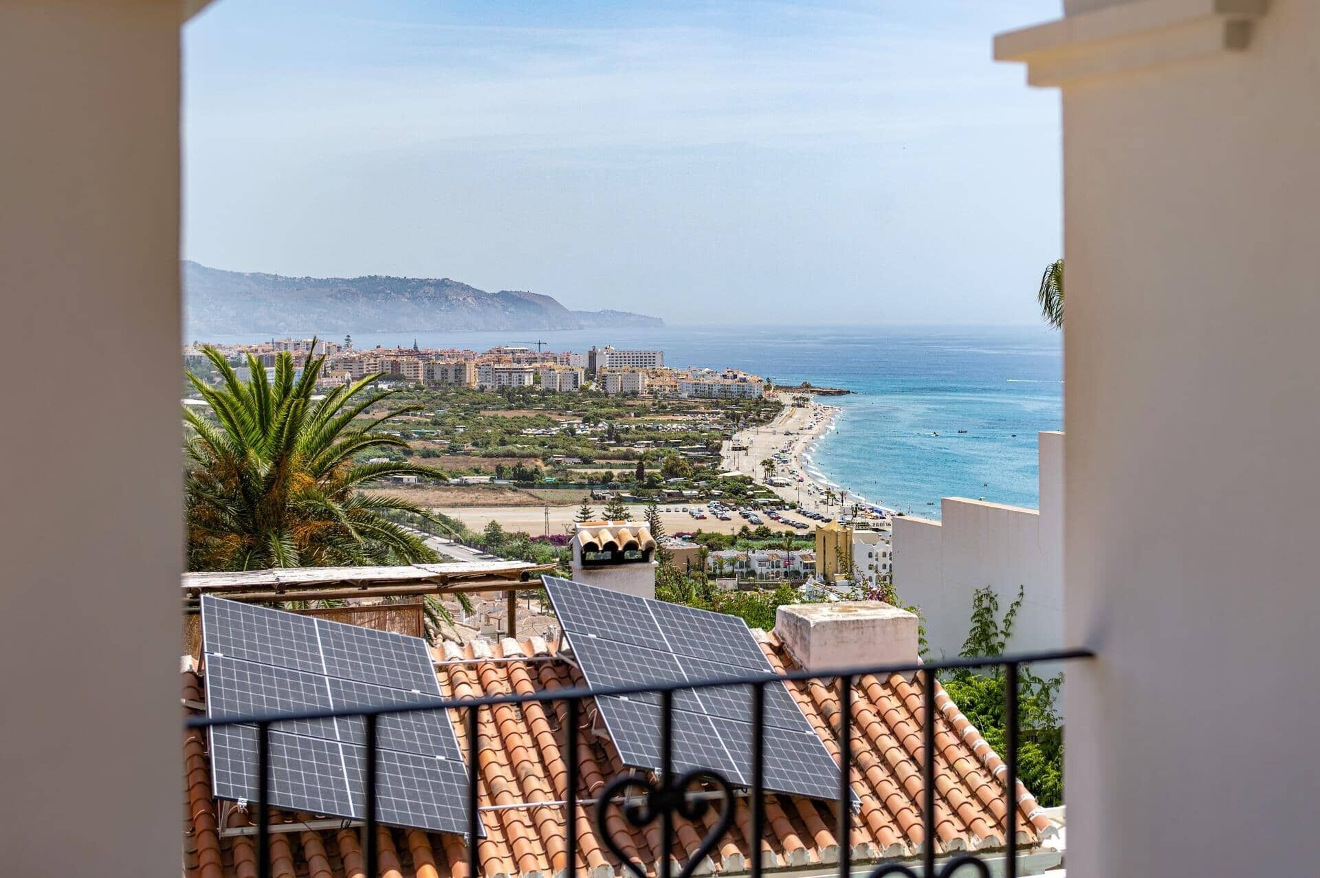 Un paysage urbain côtier offrant une vue sur la mer, des bâtiments et des panneaux solaires installés sur les toits.
