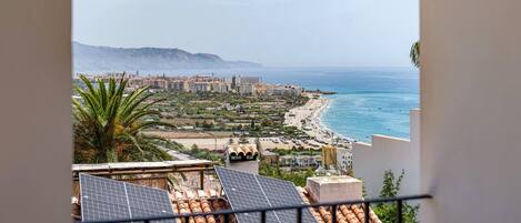 Un paysage urbain côtier offrant une vue sur la mer, des bâtiments et des panneaux solaires installés sur les toits.