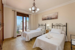 A hotel room with two beds, a balcony, a painting, and a chandelier. - Villa Lara Pinta by Villa Plus (Nerja)