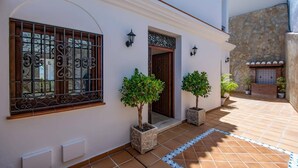A building with a white facade, a wooden door, and two potted plants. - Villa Lara Pinta by Villa Plus (Nerja)
