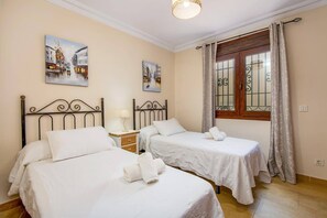 Ein Hotelzimmer mit zwei Betten, einem Nachttisch, einem Fenster mit Vorhängen und zwei Bildern an der Wand.