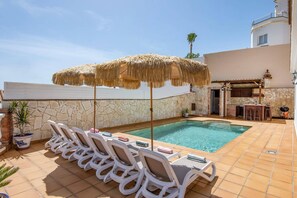 Ein Poolbereich mit Liegestühlen und einer Bar.