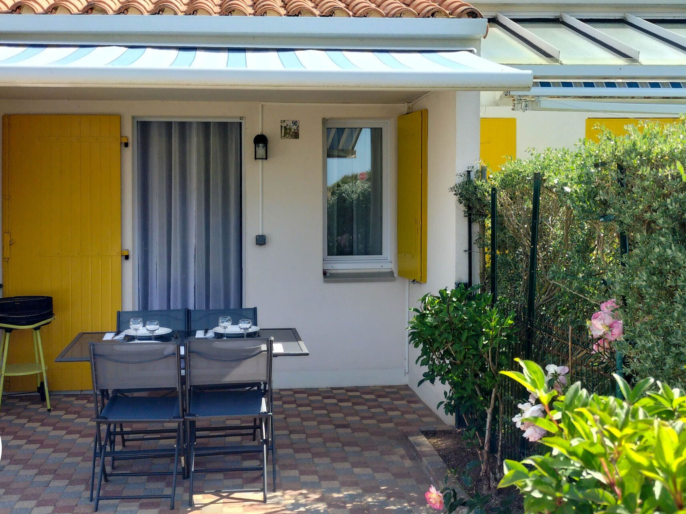 A patio with a table and chairs, a yellow door, and a window with yellow shutters.