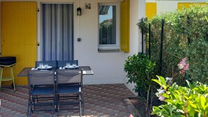 Un patio con una mesa y sillas, una puerta amarilla y un ventanal con persianas amarillas.