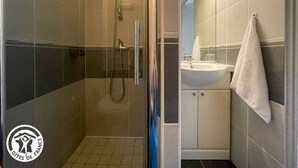 Un baño moderno con ducha acristalada, un lavamanos y una toalla colgada en la pared.