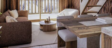 A modern living room with a wooden dining table, a sofa, and a view of a snowy landscape through a window.