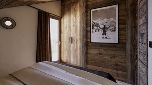 A bedroom with a wooden ceiling, a bed, a door, and a framed picture on the wall. - Apartment with mountain view - 8 guests (Méribel)