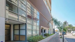 A modern building with large windows and a sloped roof. - Fully furnished apartment with TV and free internet. (São Paulo)