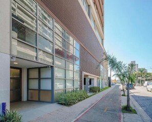 A modern building with large windows and a sloped roof. - Fully furnished apartment with TV and free internet. (São Paulo)