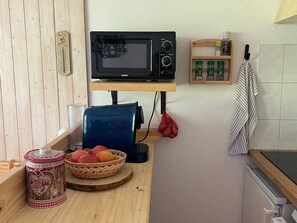 A kitchen with a microwave, a basket of fruit, a heart-shaped container, and a striped towel hanging on the wall. - Apartment, pets allowed - 4 guests (Châtel)