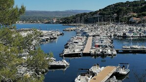 A marina with numerous boats docked, surrounded by trees and a clear view of the distant landscape. - Studio with AC and terrace - 4 guests (Saint-Cyr-sur-Mer)