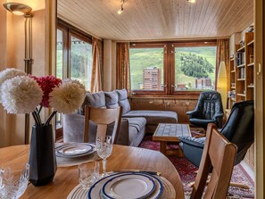 A cozy living room with a wooden ceiling, a sofa, a coffee table, and a bookshelf. - Cozy apartment, mountain view - 6 guests. (La Plagne)